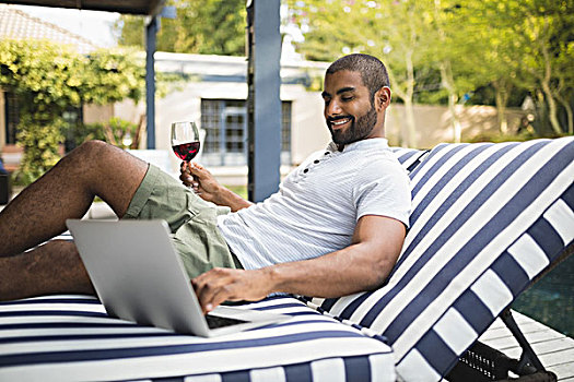 男人,拿着,葡萄酒杯,使用笔记本,休闲椅,微笑,门廊