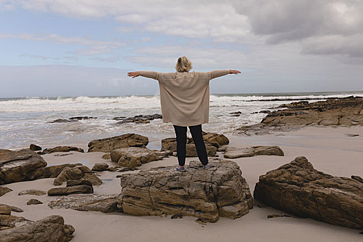 老年,女人,站立,伸展胳膊,石头,海滩