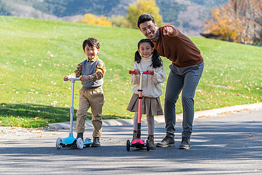 爸爸带着孩子们在玩滑板车