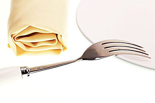 摆放整齐的黄色餐巾白色盘子和银色叉子