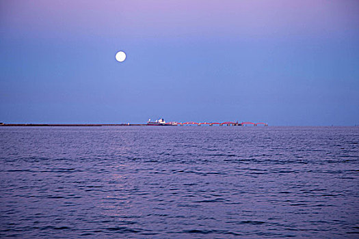 月亮下的蓝色大海和城市海岸线
