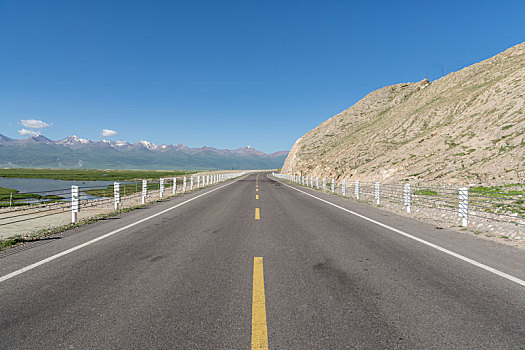 中国新疆夏季蓝天白云下高山草原g217独库公路直行道正面