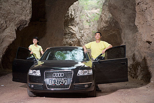 一对年轻的夫妻开着奥迪车在郊外的山洞里