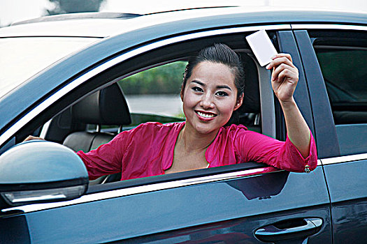 青年女人坐在车里拿着信用卡