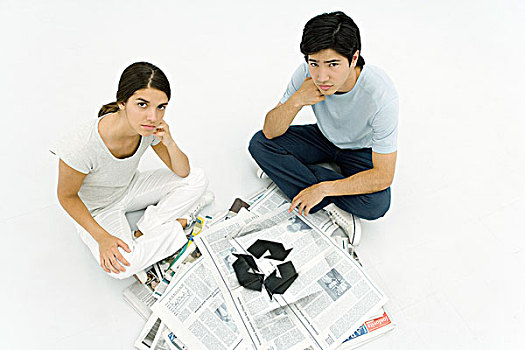年轻,情侣,坐,旁侧,一堆,报纸,回收标志,看镜头