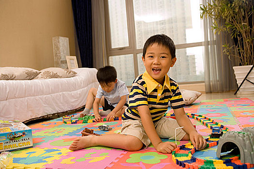 两个小男孩在地板上玩玩具