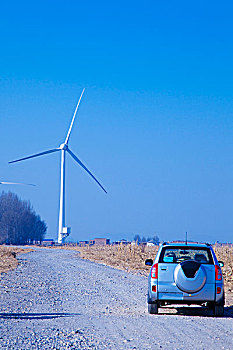 荒野公路上的车和远处的风力发电车