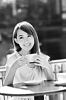 年轻女孩在露天咖啡厅喝咖啡
