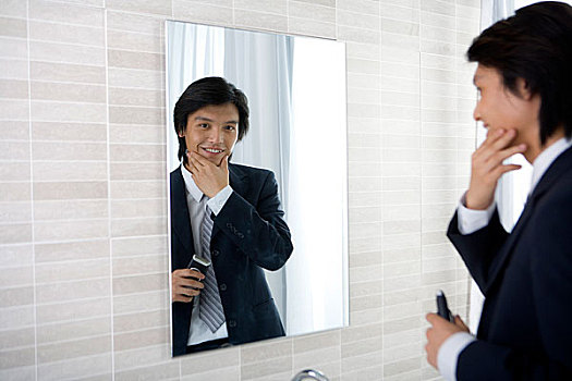 一个男人在浴室内对着镜子准备刮胡子