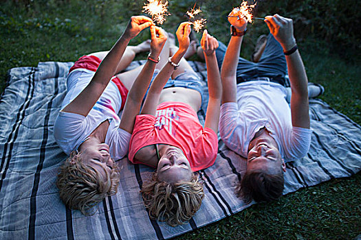 三个,年轻人,朋友,躺着,野餐毯,公园,拿着,向上,闪闪发光