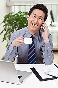 一个在办公室喝咖啡用电脑的青年商务男士