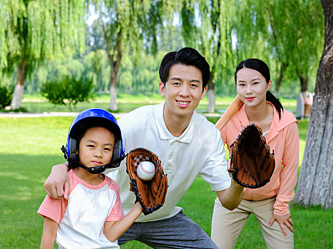 快乐的三口之家在公园打棒球