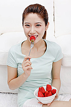 年轻女士坐在沙发旁吃草莓