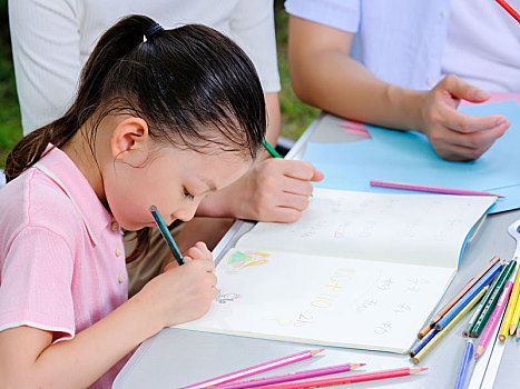 年轻的父母在户外辅导孩子写作业