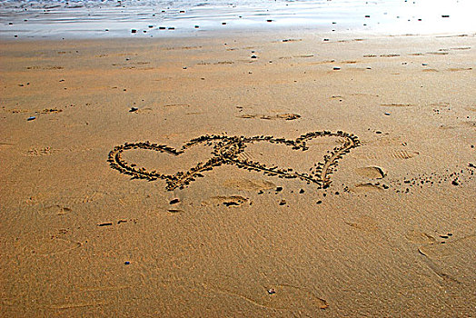 海滩上画着两个心型的图案叠在一起