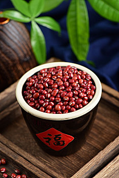 复古中国风格背景上放在福字水缸里的红小豆特写图片