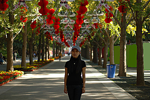 一名年轻女性站在挂满红色灯笼的街道上