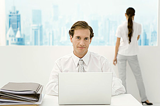 商务人士,坐,笔记本电脑,看镜头,微笑,同事,向窗外看,背景