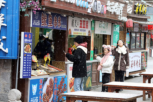 山东省日照市,小年迎来初雪,市民雪中漫步东夷小镇