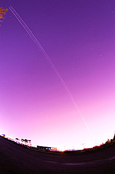一架正在起飞中的飞机的灯光在夜空中形成了美丽的弧线