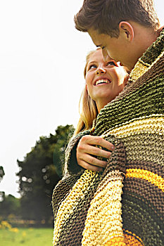 微笑的夫妇裹在毛毯