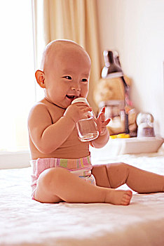 抱着奶瓶笑的婴儿