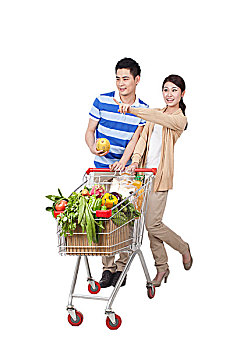 一对青年男女合推一辆装满蔬菜的购物车