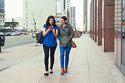 两个,女性朋友,走,街道,看,智能手机