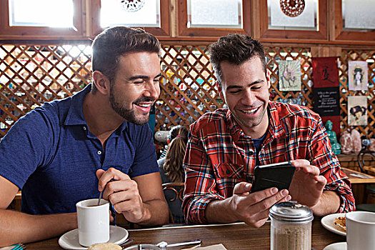 两个,男性,朋友,看,智能手机,餐馆,酒吧