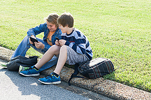 两个男孩,坐,路边,手持,电子产品