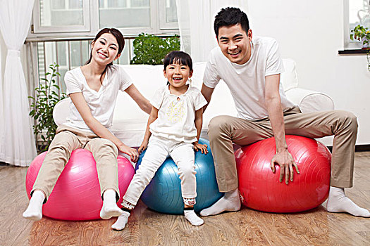三口之家坐在彩色健身球上