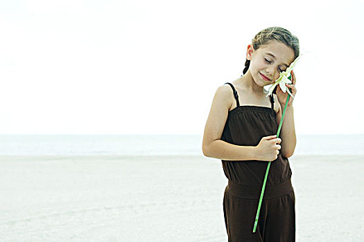 女孩,站立,海滩,拿着,花,向上,脸颊,闭眼,微笑