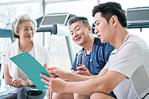 老年夫妇在私教的指导下在健身房健身