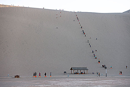 攀爬鸣沙山沙丘的游客
