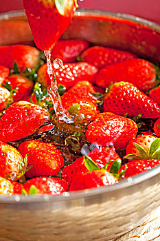 一个鲜红色草莓悬在半空中的特写正在滴水