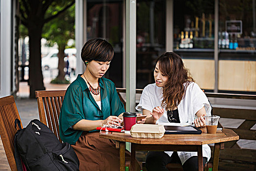 两个女人,黑发,穿,绿色,白衬衫,坐,桌子,街头咖啡馆,看,数码