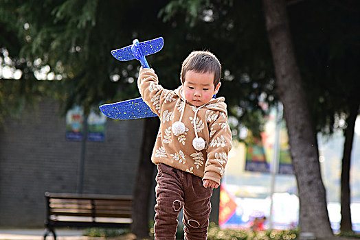秋天草坪上玩飞机的小男孩