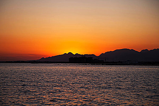 红色夕阳照映下的大海和城市的海岸线