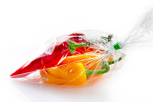 一袋红色与黄色的新鲜甜椒在白色的背景