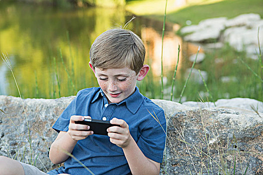 男孩,户外,坐,石头,手持,电子游戏