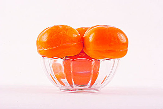 一个透明的玻璃碗中盛着柿子