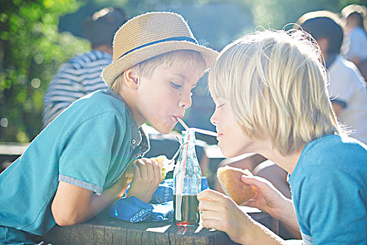 两个男孩,用瓶子喝,吸管
