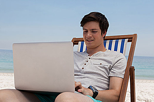 男人,坐,太阳椅,使用笔记本,海滩,微笑