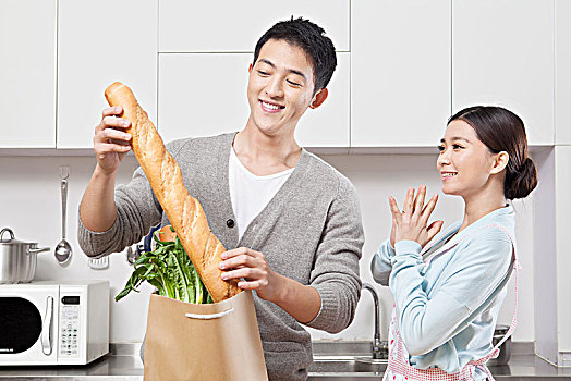 手拿紙袋子在廚房里的情侶