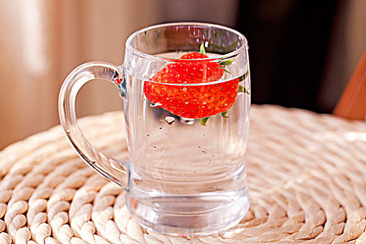 红色新鲜的草莓泡在水杯中的特写