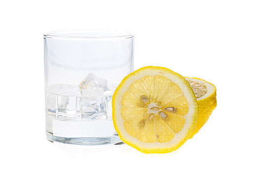 一片新鲜的切开的柠檬摆放在一个盛有冰块的玻璃水杯旁边