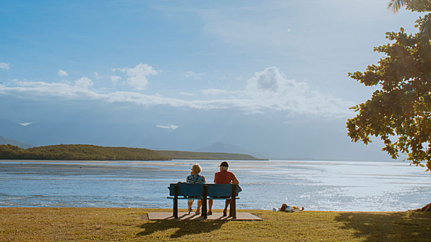 澳大利亚凯恩斯棕榈湾海边长椅上的幸福老夫妻