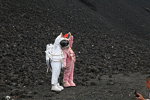 内蒙古火山口游客穿宇航服拿国旗拍照,宛若登陆外星球