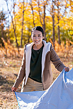 快乐的年轻女子秋游搭帐篷