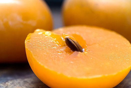 切开的,成熟的香蜜甜柿子摆放在陈旧的木板上